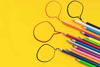 colored pencils on a yellow background drawing dialogue clouds